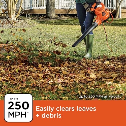 Person using a leaf blower to clear leaves in a garden.