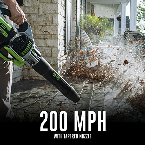 Person using a leaf blower on a patio with leaves flying.